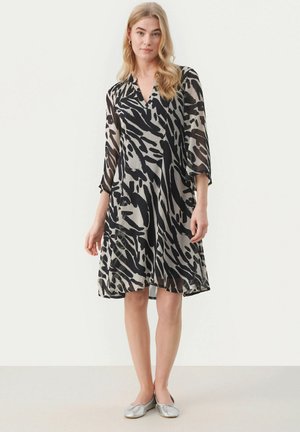 Abito stampato in bianco e nero con scollatura a V, maniche a tre quarti e silhouette fluida. Realizzato in tessuto leggero, lunghezza al ginocchio.