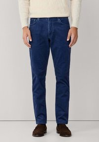 Pantalones de pana azul marino con un diseño de pierna recta, estilo de cinco bolsillos y una textura suave, combinados con un suéter de punto en trenzas color beige claro.