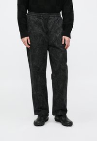 Μαύρο παντελόνι με μοτίβο και άνετη εφαρμογή, με ελαστική μέση, κορδόνι και δύο πλαϊνές τσέπες. Υφή υφάσματος με λεπτό σχέδιο.