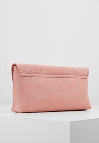Soft pink suede clutch bag with a flap closure, displayed on a white surface against a plain light gray background.
