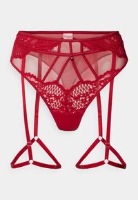 Lingerie en dentelle rouge avec un design transparent, des bretelles décoratives et des motifs intriqués. Détail avec un charme central et des bords festonnés.