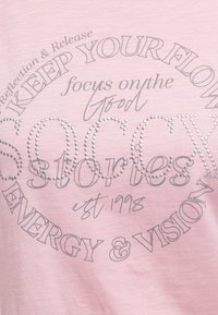 Pink fabric with text "KEEP YOUR FLOW," "focus on the good," "SOCK stories," "est. 1998," and "ENERGY & VISION" in various fonts and styles.