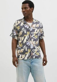 Chemise à manches courtes avec une base grise et un motif floral en crème, vert et violet. Présente une coupe décontractée et des fermetures à boutons.