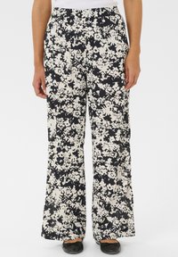 Pantalons larges à fleurs en tissu noir et blanc. Caractéristiques : taille élastique et coupe ample. Imprimé floral couvrant toute la surface.