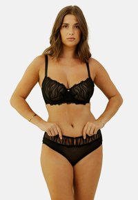 Bralette en dentelle noire avec tissu transparent et bords festonnés, dotée de renforts et de bretelles réglables ; culottes hautes noires transparentes assorties.
