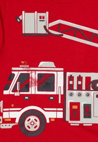 Czerwona koszulka z grafiką wozu strażackiego, z szarymi i białymi detalami, w tym oknami, kołami i drabiną.