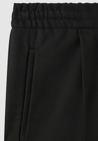 Pantalons noirs avec une taille élastique, dotés d'une texture lisse et de poches latérales, fabriqués en tissu tissé avec un léger éclat.