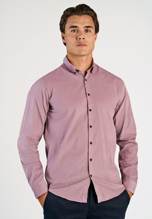 Chemise à manches longues de couleur mauve clair avec un col boutonné. Elle présente une texture lisse, des boutons noirs et une coupe classique.