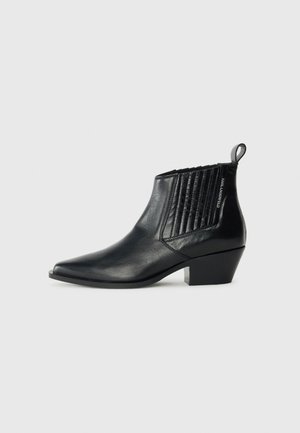Bottine en cuir noir avec un bout pointu, panneau latéral matelassé et un talon bloc bas. Marquage discret sur le côté.