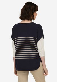 Námořnický modrý top s krémovými vodorovnými pruhy na zádech, volného střihu, s lodičkovým výstřihem a rukávy do lokte. Měkký materiál.