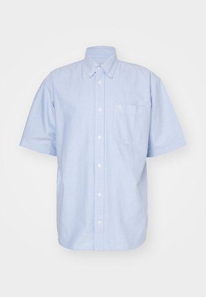 Camisa de botones de manga corta en algodón de color azul claro. Presenta cuello tipo solapa y un bolsillo en el frente. Diseño sencillo de color sólido.