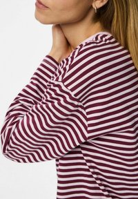 Dlouhý rukáv top v burgundské a světle růžové pruhy, vyrobený z měkké tkaniny. Obsahuje kulatý výstřih a volný střih.