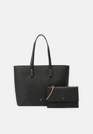 Saco tote em imitação de pele preta com textura lisa, duas alças longas e um pequeno pouch destacável com corrente em destaque. Design simples e retangular.
