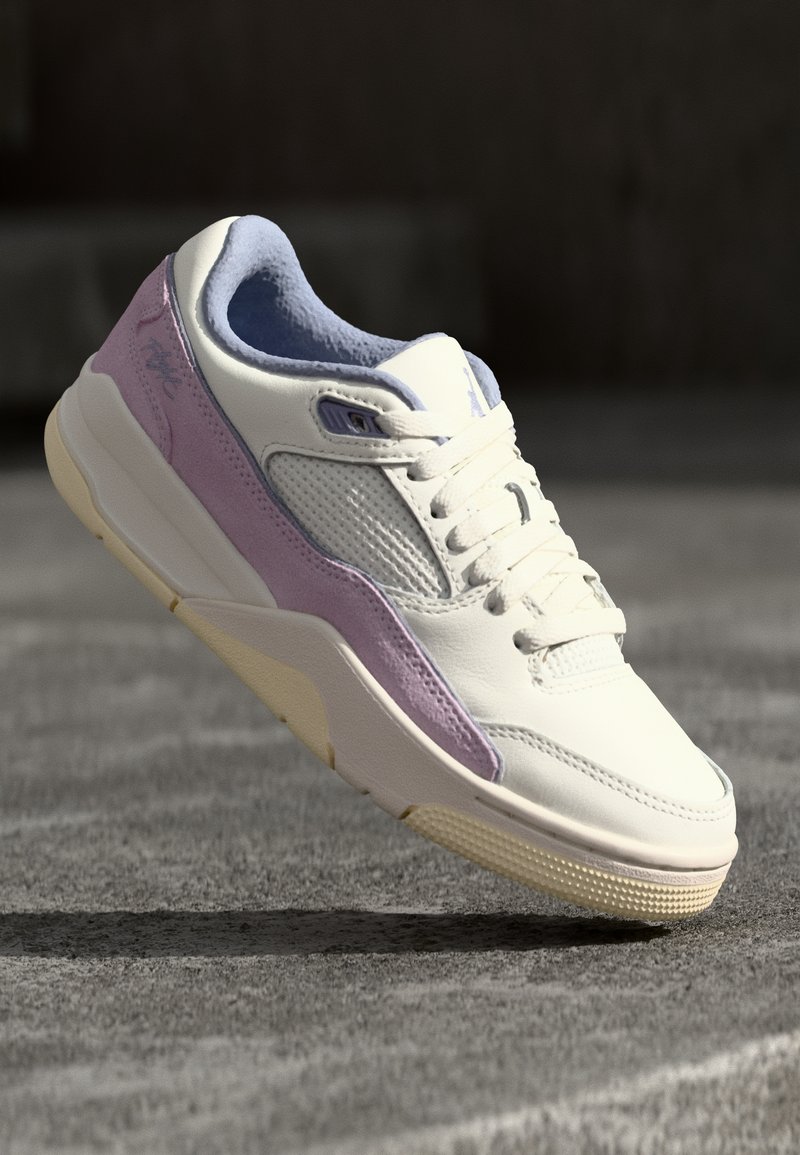 Baskets blanches et violet clair avec des détails en mesh et cuir, montrées en plein air au-dessus d'une surface grise rugueuse.
