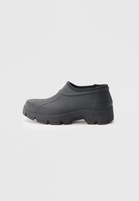 Black rubber slip-on shoes with a rounded toe and textured sole, featuring a smooth upper and a raised edge around the opening.