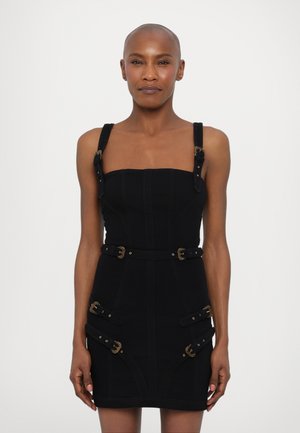 Schwarzes Denim-Minikleid mit eckigem Ausschnitt, verstellbaren Trägern, goldenen Metallakzenten und Schnallen-Details an der Taille und den Seiten.