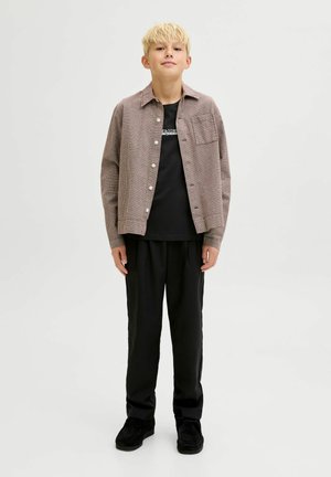 Rood-witte geblokte blouse met knopen, zwart t-shirt, zwarte broek, zwarte schoenen. Slim fit met een zak op de borst. Glad textuur.