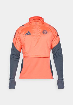 Sudadera deportiva en color naranja y gris oscuro con media cremallera, mangas largas, logo y diseño de cintura entallada. Presenta un tejido texturizado.