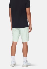 Sort kortærmet skjorte kombineret med lyse mintgrønne shorts. Hvide sokker og sneakers fuldender outfittet. Ingen synlige mønstre eller accenter.