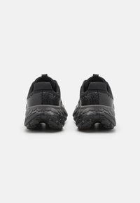 Zapatos deportivos negros con una parte superior de malla texturizada, talón reforzado y una suela gruesa y con patrón para una mejor tracción y soporte.