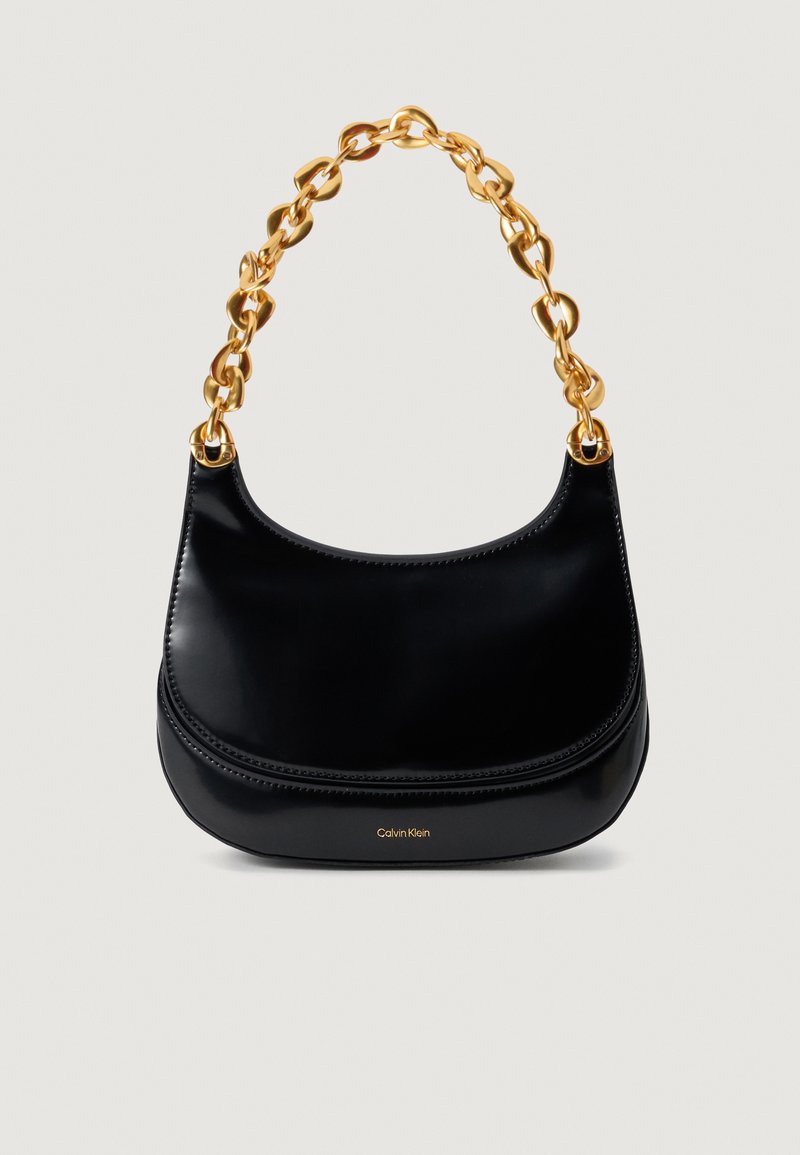 Must must rõngas kehaga must nahast käekott, millel on sujuv tekstuur ja suur kuldne ahel. Esiküljel on reljeefne "Calvin Klein" logo.