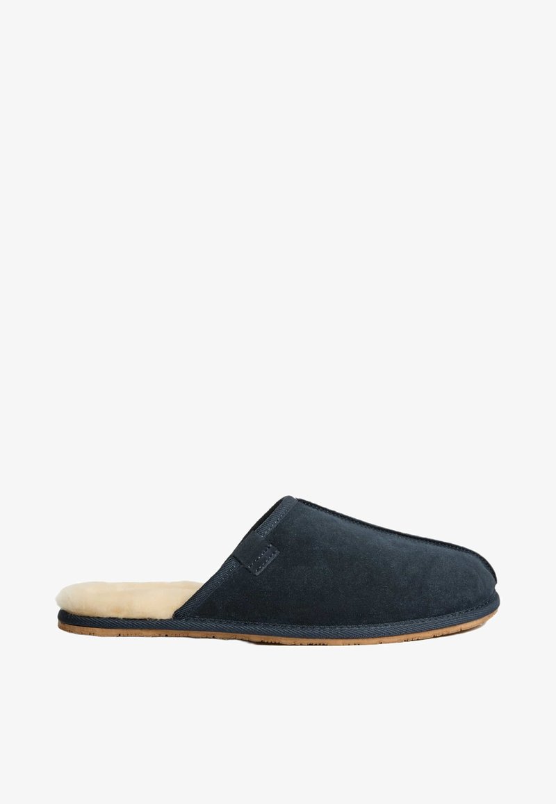 Mørkeblå ruskinds-slipper med en blød pelsfór. Har en lukket tå og åben rygdesign; gummisål for godt greb.