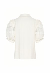 Camicia bianca in lino con colletto e maniche corte a sbuffo, caratterizzata da dettagli in pizzo floreale intricato. Tessuto morbido, silhouette rilassata.