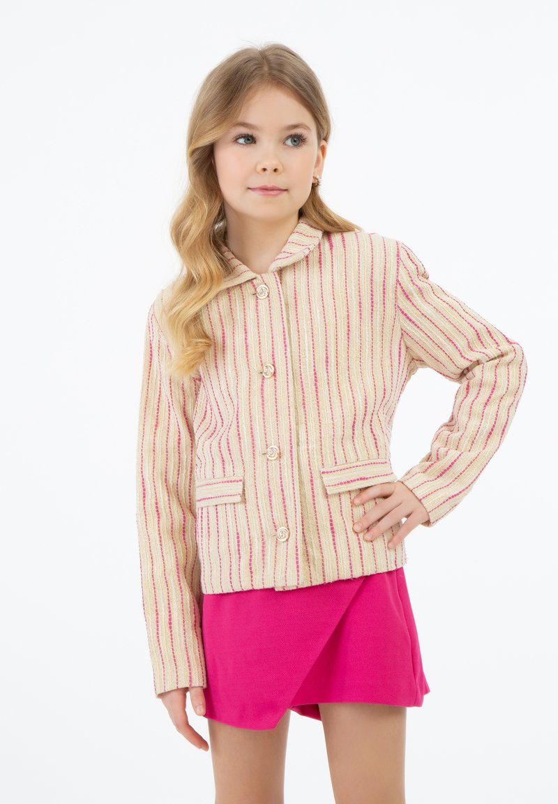 Giacca a righe multicolore in beige con accenti rosa, dotata di colletto, chiusura a bottoni e tasche frontali. Indossata sopra una gonna rosa.