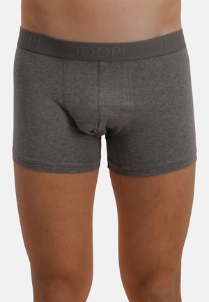 Muž nosící tmavě šedé boxerky s širokým páskem s logem "JOOP!" na jednobarevném pozadí.