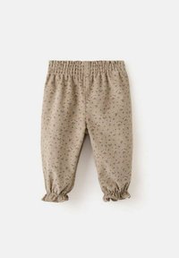 Bež hlače z rožnim vzorcem, elastičnim pasom in nabranimi manšetami. Izdelane iz teksturirane tkanine z majhnimi, subtilnimi cvetličnimi motivi.