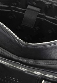 Interiorul unei genți din piele neagră cu textură netedă, închidere cu fermoar și multiple compartimente. Căptușită cu un material textil negru, având un model discret cu logo.