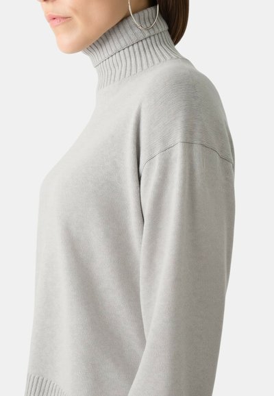 Maglione a collo alto grigio chiaro con scollo a coste e tessuto testurizzato. Presenta spalle leggermente oversize e maniche lunghe.