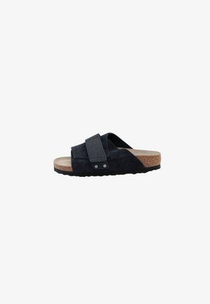 Black suede slide sandal with a wide strap and adjustable buckle, cork footbed, and textured rubber sole for grip.