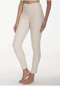 Beige Leggings mit hohem Bund, seitlichen Taschen und schlankem, tapered Schnitt. Hergestellt aus einem weichen, dehnbaren Stoff.