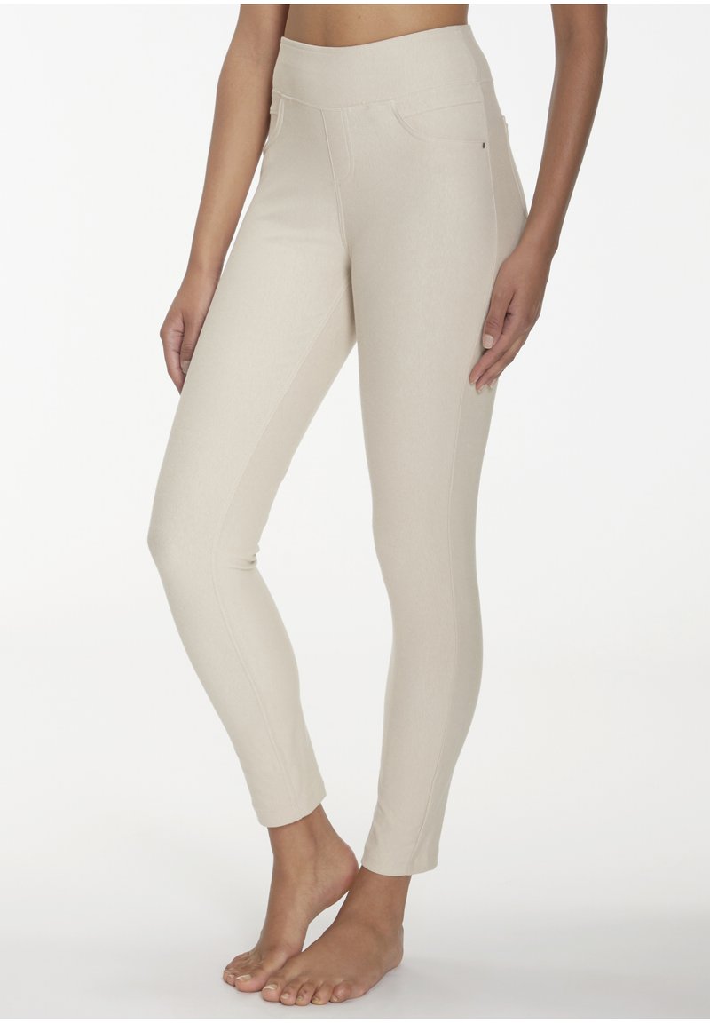 Beige Leggings mit hohem Bund, seitlichen Taschen und schlankem, tapered Schnitt. Hergestellt aus einem weichen, dehnbaren Stoff.