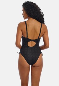 Sort mønstret ét-styk swimsuit med justerbare stropper, udskæring på ryggen og snore i siderne, der viser et tekstureret design.