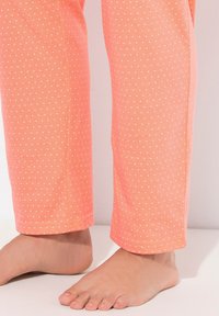 Lätta, korallfärgade pyjamasbyxor med ett prickigt mönster i vitt. Rakt snitt med en mjuk textur och elastisk midja.