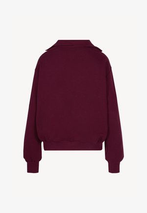 Donkerpaarse trui met lange mouwen, geribbelde manchetten, tailleband en kraag, gezien van achteren tegen een witte achtergrond.