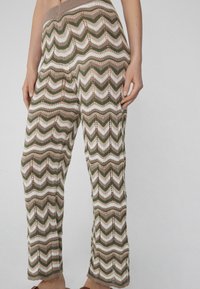 Gebreide broek met een zigzagpatroon in groen, beige en wit. Ze hebben een brede elastische tailleband en een open gebreide structuur.