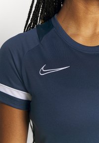 Laivaston urheilupaita lyhyillä hihoilla, jossa on valkoisia yksityiskohtia. Nike-logon brodeeraus valkoisena vasemmassa olkapaikassa. Pehmeä pinta.