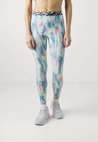 Leggins attillati multicolori con una base blu chiaro, caratterizzati da motivi astratti rosa e acquamarina e una vita a righe bianco e nero.