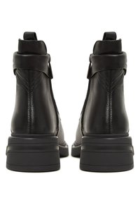Botine din piele neagră până la gleznă, cu închidere tip fermoar, toc structurat și panouri texturate la spate. Talpa din cauciuc plat oferă stabilitate.