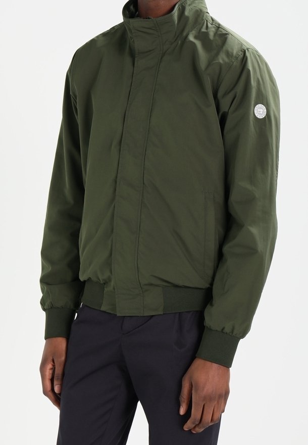 Groene bomberjack met een hoge kraag, ribgebreide manchetten en zoom. Gemaakt van lichtgewicht materiaal, met een logopatch op de linker mouw.