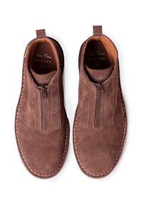 Bruine suède enkellaarzen met een ritssluiting, rubberen zool en decoratieve stiksels. Het interieur heeft een beige voering met merkinscripties.