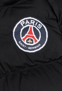 Mustaa kangasta, jossa on pyöreä logo, jossa on "PARIS" ylhäällä, punainen Eiffel-torni ja "SAINT-GERMAIN" alhaalla sinisellä ääriviivalla.