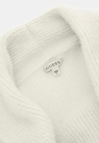 Witte, zachte gebreide trui met een geribbelde textuur rond de halslijn. Bevat een 'GUESS'-label, dat het merk en de maat aangeeft.