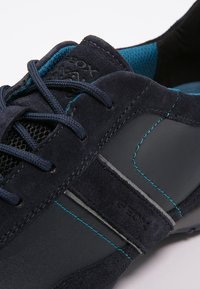 Granatowe buty wykonane z zamszu i materiałów syntetycznych, z siateczkowymi panelami, kontrastującymi turkusowymi przeszyciami oraz logo Geox z boku.