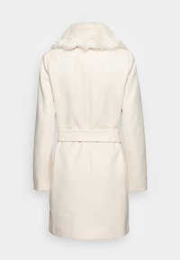 Kremfarget frakk med krage av kunstpels, lange ermer, belted midje og glatt teksturert stoff. Enkel og elegant design.