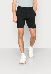 Schwarze Sportshorts aus Baumwollmischung, mit elastischem Bund und Kordelzug, seitlichen Taschen und einer einfachen, glatten Textur.