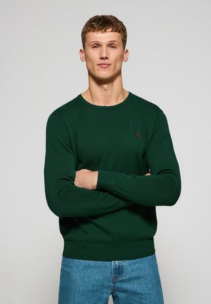 Maglione in cotone verde scuro con collo rotondo, maniche lunghe e polsini a coste. Presenta un piccolo logo rosso sul lato sinistro del petto.